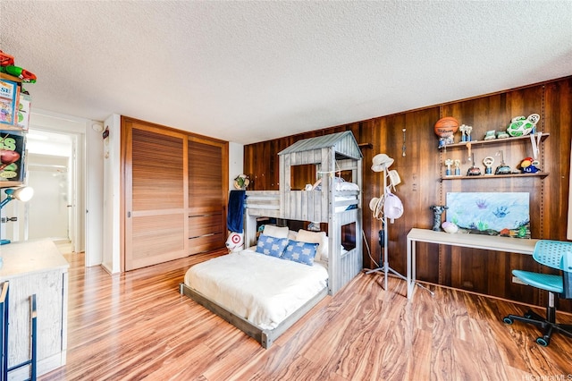 250 Kawaihae St Unit 10E, Honolulu, HI 96825 - bedroom featuring a textured ceiling, wood finished floors, wood walls, and a closet