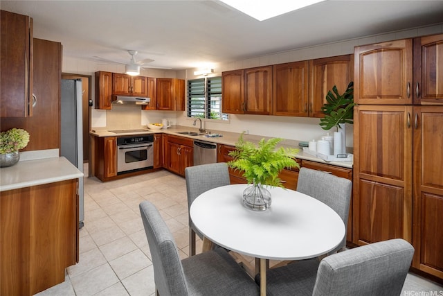 1456 Ala Aolani St, Honolulu, HI 96819 - kitchen with stainless steel appliances, under cabinet range hood, a sink, light tile patterned floors, and brown cabinetry