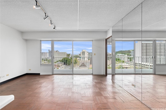 1333 Heulu St Unit 901, Honolulu, HI 96822 - unfurnished room featuring baseboards, a textured ceiling, plenty of natural light, a city view, and track lighting