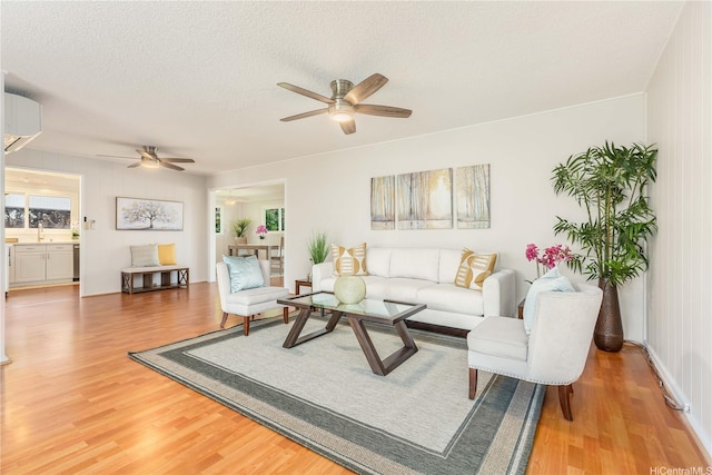 1433 Akanahe Pl, Kailua, HI 96734 - living area with a ceiling fan, a wall unit AC, light wood-style flooring, and a textured ceiling