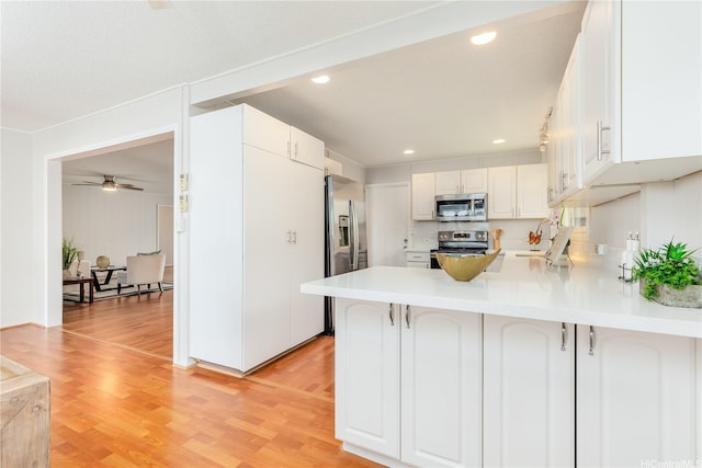 1433 Akanahe Pl, Kailua, HI 96734 - kitchen with stainless steel appliances, a peninsula, light wood finished floors, ceiling fan, and white cabinetry