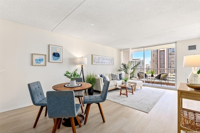 400 Hobron Ln Unit 1807, Honolulu, HI 96815 - dining room featuring light wood-style floors, a wall of windows, and a textured ceiling