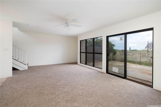 spare room featuring carpet flooring, ceiling fan, and stairs