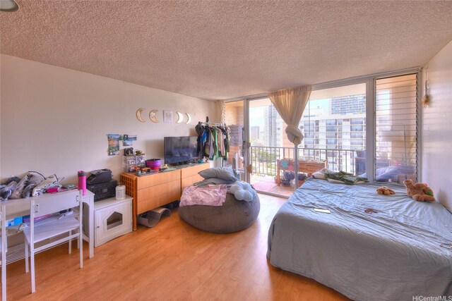 2345 Ala Wai Blvd Unit 2210, Honolulu, HI 96815 - bedroom featuring a wall of windows, light wood-style flooring, access to outside, and a textured ceiling