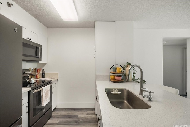 3009 Ala Makahala Pl Unit 214, Honolulu, HI 96818 - kitchen with stainless steel appliances, a textured ceiling, dark wood-type flooring, white cabinetry, and a peninsula