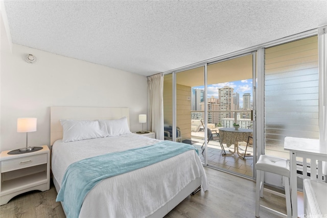 445 Seaside Ave Unit 1602, Honolulu, HI 96815 - bedroom featuring expansive windows, access to exterior, wood finished floors, a view of city, and a textured ceiling