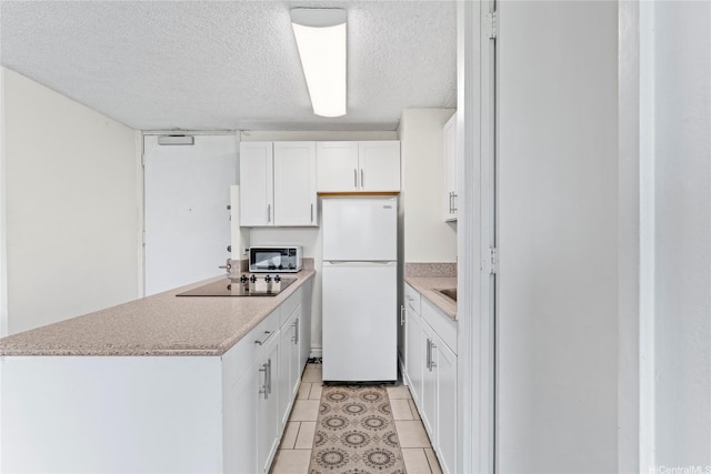 445 Seaside Ave Unit 1602, Honolulu, HI 96815 - kitchen with freestanding refrigerator, black electric stovetop, white cabinetry, a textured ceiling, and light countertops