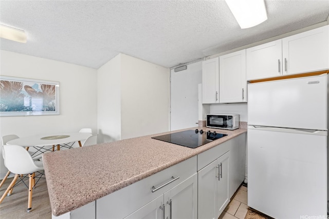 445 Seaside Ave Unit 1602, Honolulu, HI 96815 - kitchen with black appliances, white cabinets, a textured ceiling, and a peninsula