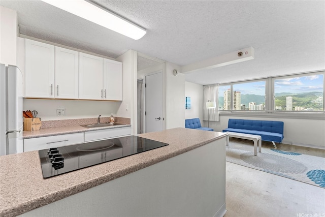 445 Seaside Ave Unit 1602, Honolulu, HI 96815 - kitchen with black electric stovetop, white cabinetry, a textured ceiling, light countertops, and open floor plan
