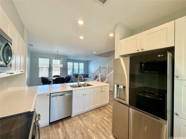 91-2220 Kaiwawalo St Unit 11-1105, Ewa Beach, HI 96706 - kitchen featuring stainless steel appliances, white cabinets, light wood-style flooring, a peninsula, and open floor plan