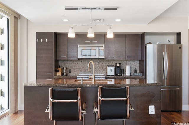 1837 Kalakaua Ave Unit 2001, Honolulu, HI 96815 - kitchen with appliances with stainless steel finishes, dark brown cabinetry, a center island with sink, and backsplash