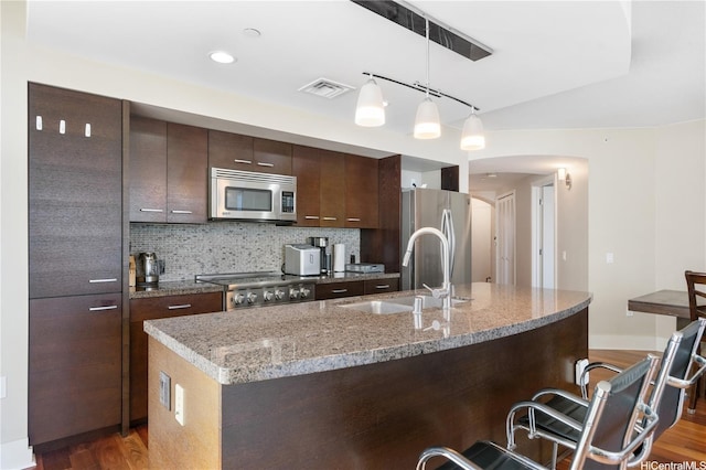 1837 Kalakaua Ave Unit 2001, Honolulu, HI 96815 - kitchen featuring appliances with stainless steel finishes, a kitchen breakfast bar, arched walkways, light wood-style flooring, and tasteful backsplash