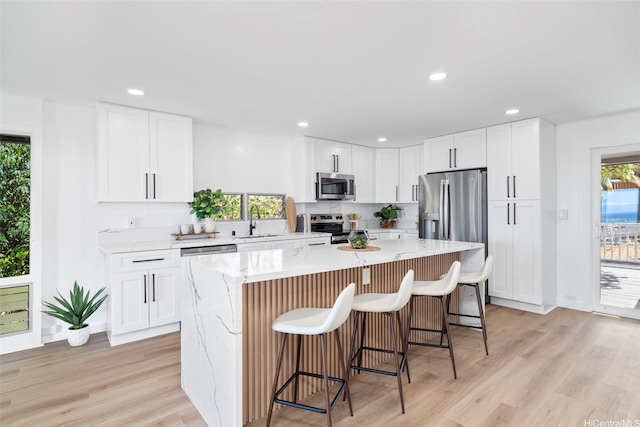 1076 Ilima Dr Unit A, Honolulu, HI 96817 - kitchen featuring appliances with stainless steel finishes, a kitchen island, a kitchen bar, light wood-style flooring, and recessed lighting