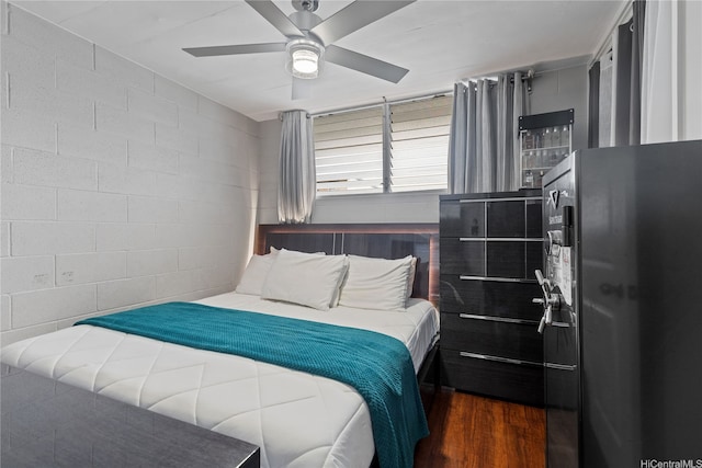 715 Umi St Unit 2B, Honolulu, HI 96819 - bedroom with dark wood-type flooring, ceiling fan, freestanding refrigerator, and concrete block wall