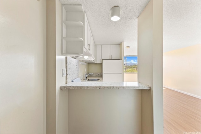 1060 Kamehameha Hwy Unit 801A, Pearl City, HI 96782 - kitchen featuring freestanding refrigerator, open shelves, white cabinets, a textured ceiling, and wood finished floors