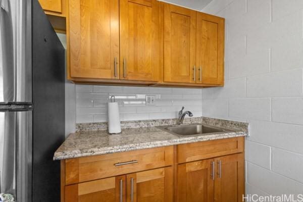 94-333 Hokuahiahi St Unit 103, Mililani, HI 96789 - kitchen featuring freestanding refrigerator, tasteful backsplash, brown cabinets, and light stone countertops