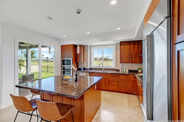 91-1227 Kuanoo St, Ewa Beach, HI 96706 - kitchen with appliances with stainless steel finishes, brown cabinetry, a kitchen breakfast bar, decorative backsplash, and a kitchen island