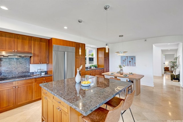 91-1227 Kuanoo St, Ewa Beach, HI 96706 - kitchen featuring built in fridge, under cabinet range hood, black electric cooktop, decorative backsplash, and a kitchen breakfast bar