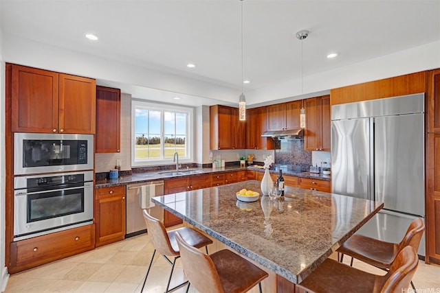 91-1227 Kuanoo St, Ewa Beach, HI 96706 - kitchen with built in appliances, under cabinet range hood, brown cabinets, a breakfast bar, and decorative backsplash