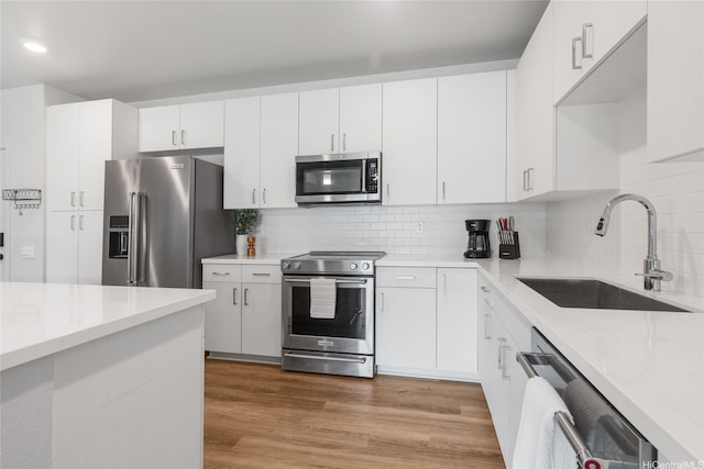 91-3575 Iwikuamoo St Unit 9104, Ewa Beach, HI 96706 - kitchen with appliances with stainless steel finishes, decorative backsplash, white cabinetry, light wood-style flooring, and recessed lighting