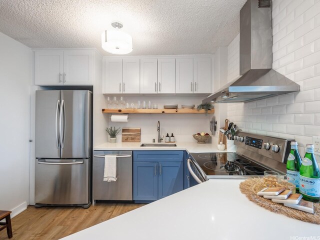 1545 Nehoa St Unit 101, Honolulu, HI 96822 - kitchen with stainless steel appliances, wall chimney range hood, light wood finished floors, light countertops, and blue cabinetry