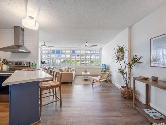 1545 Nehoa St Unit 101, Honolulu, HI 96822 - kitchen with electric range, wall chimney range hood, a textured ceiling, a kitchen bar, and a ceiling fan