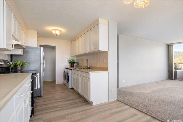2825 S King St Unit 2403, Honolulu, HI 96826 - kitchen featuring black range with electric stovetop, washer / clothes dryer, under cabinet range hood, decorative backsplash, and light countertops