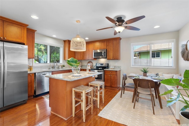 66-912 Kamakahala St Unit 2, Waialua, HI 96791 - kitchen featuring appliances with stainless steel finishes, brown cabinetry, a center island, a kitchen breakfast bar, and light wood-style floors
