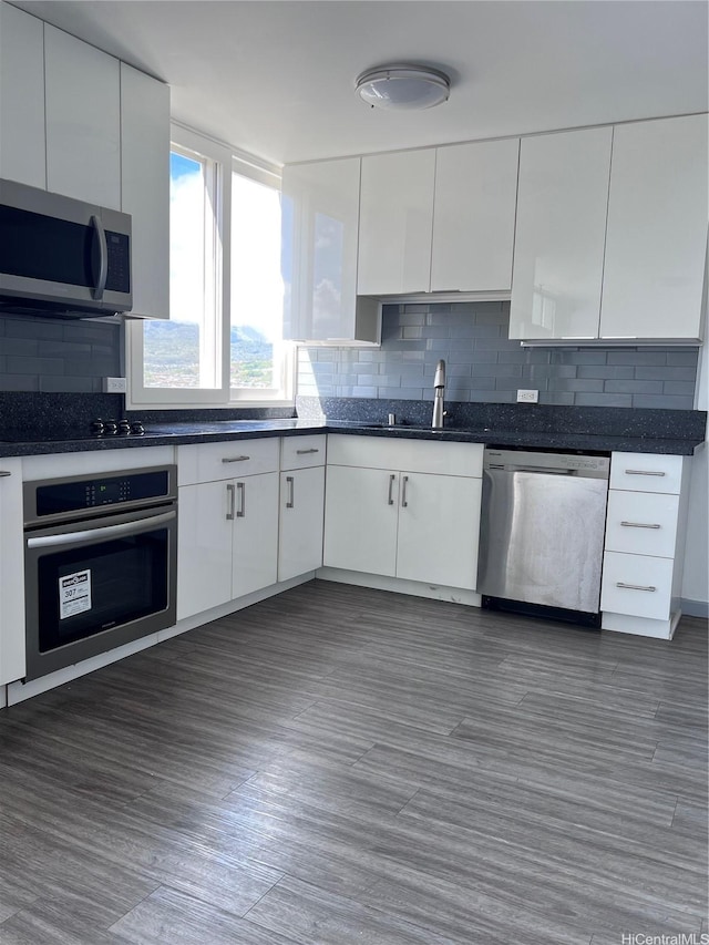 5210 Likini St Unit 901, Honolulu, HI 96818 - kitchen featuring stainless steel appliances, white cabinetry, dark countertops, backsplash, and modern cabinets
