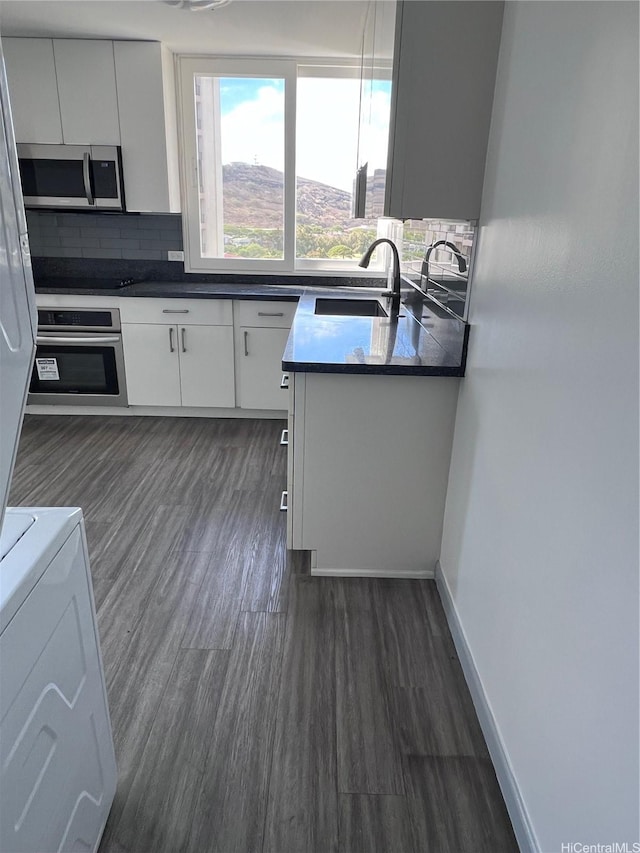 5210 Likini St Unit 901, Honolulu, HI 96818 - kitchen featuring appliances with stainless steel finishes, decorative backsplash, dark wood finished floors, dark countertops, and white cabinets
