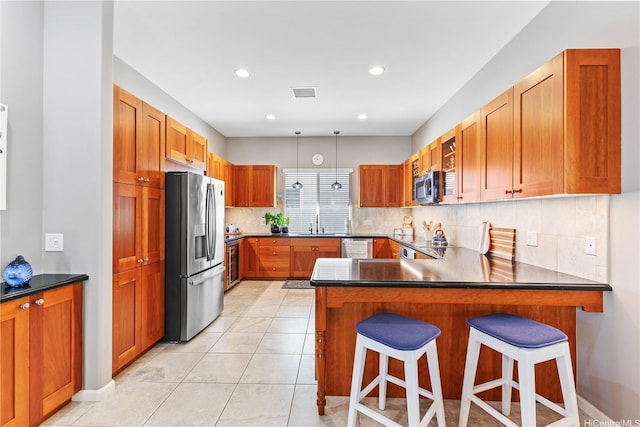 91-1100 Waiemi St, Ewa Beach, HI 96706 - kitchen featuring appliances with stainless steel finishes, tasteful backsplash, a peninsula, dark countertops, and brown cabinetry