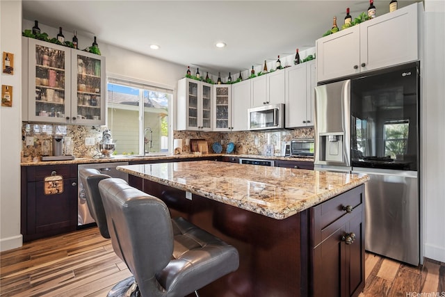 91-1108 Kaihohonu St, Ewa Beach, HI 96706 - kitchen featuring appliances with stainless steel finishes, wood finished floors, a kitchen island, a kitchen bar, and tasteful backsplash