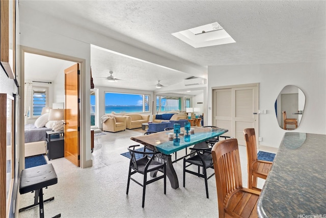 68-665 Hoomana Pl, Waialua, HI 96791 - dining room featuring a textured ceiling, a wall mounted air conditioner, a skylight, a water view, and vaulted ceiling