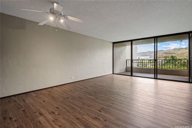 500 Lunalilo Home Rd Unit 24K, Honolulu, HI 96825 - empty room featuring a textured ceiling, wood finished floors, expansive windows, a textured wall, and ceiling fan