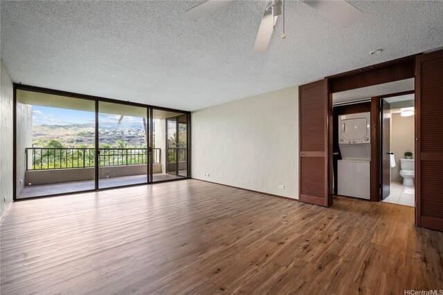 500 Lunalilo Home Rd Unit 24K, Honolulu, HI 96825 - unfurnished room featuring stacked washing machine and dryer, wood finished floors, a textured ceiling, a wall of windows, and ceiling fan