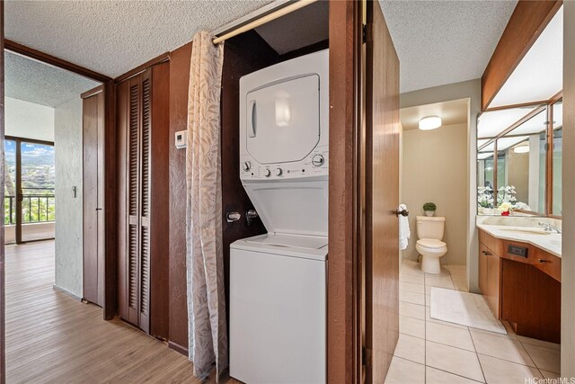 500 Lunalilo Home Rd Unit 24K, Honolulu, HI 96825 - washroom with stacked washer and clothes dryer, a textured ceiling, and light wood-style floors