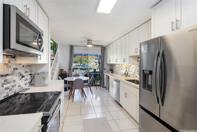 239 Mananai Pl Unit 54H, Honolulu, HI 96818 - kitchen with appliances with stainless steel finishes, backsplash, light countertops, white cabinets, and light tile patterned floors