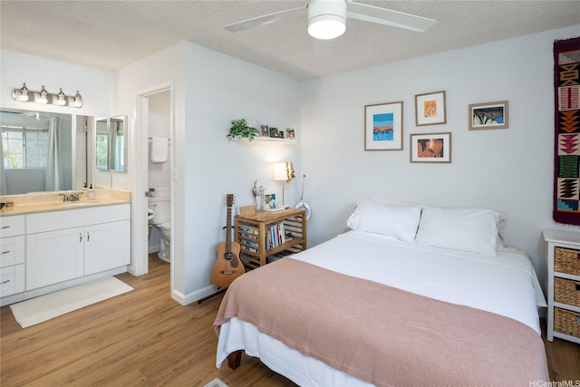 239 Mananai Pl Unit 54H, Honolulu, HI 96818 - bedroom featuring light wood-style floors, a textured ceiling, ensuite bath, and ceiling fan