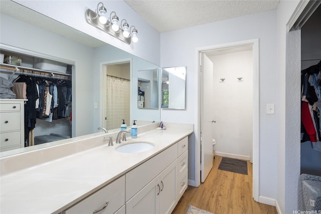 239 Mananai Pl Unit 54H, Honolulu, HI 96818 - bathroom with wood finished floors, vanity, a walk in closet, and a textured ceiling