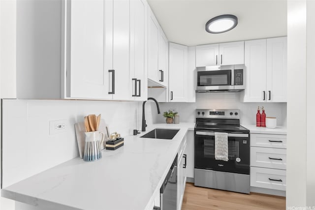 5055 Likini St Unit D226, Honolulu, HI 96818 - kitchen with appliances with stainless steel finishes, white cabinets, decorative backsplash, light stone countertops, and light wood-style flooring