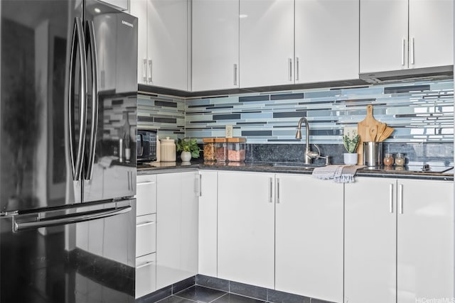 747 Amana St Unit 2206, Honolulu, HI 96814 - kitchen with freestanding refrigerator, white cabinetry, dark stone countertops, and backsplash