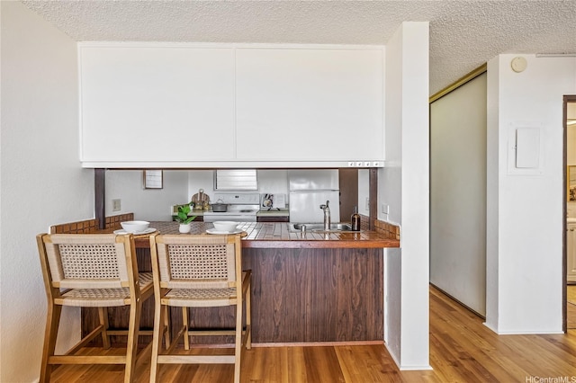 98-099 Uao Pl Unit 506, Aiea, HI 96701 - kitchen with white appliances, wood finished floors, a textured ceiling, and a peninsula