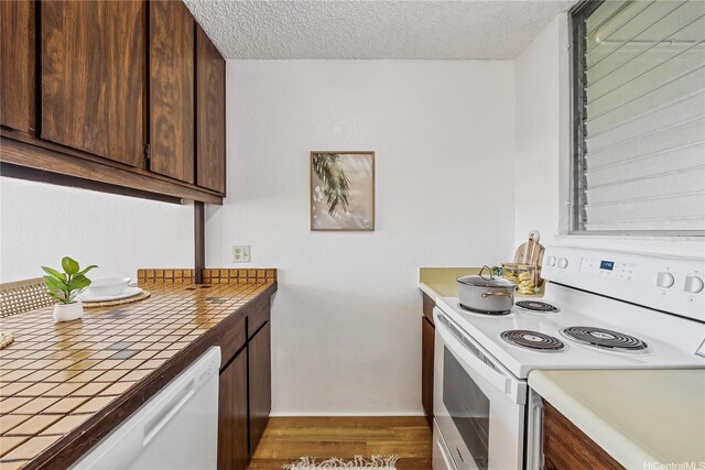 98-099 Uao Pl Unit 506, Aiea, HI 96701 - kitchen with white appliances, tile countertops, dark brown cabinets, light wood-type flooring, and a textured ceiling