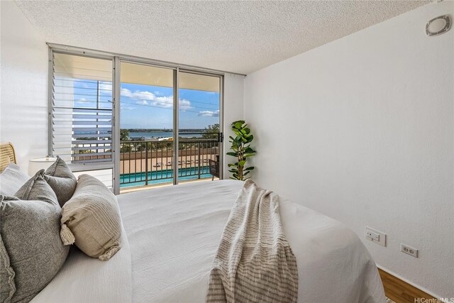 98-099 Uao Pl Unit 506, Aiea, HI 96701 - bedroom with access to exterior, a water view, a textured ceiling, wood finished floors, and floor to ceiling windows