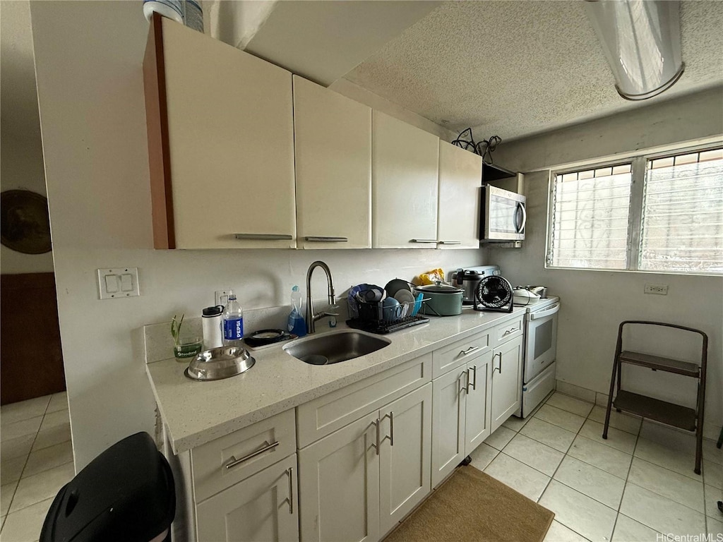 908 University Ave Unit A105, Honolulu, HI 96826 - kitchen featuring electric stove, stainless steel microwave, light tile patterned floors, white cabinetry, and a textured ceiling