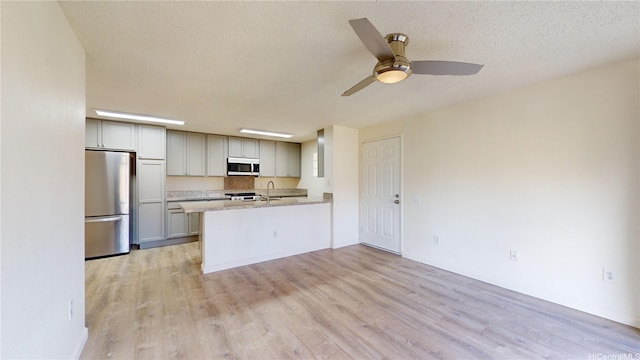 91-1201 Kaneana St Unit 3J, Ewa Beach, HI 96706 - kitchen with appliances with stainless steel finishes, a peninsula, light wood-style floors, a textured ceiling, and ceiling fan