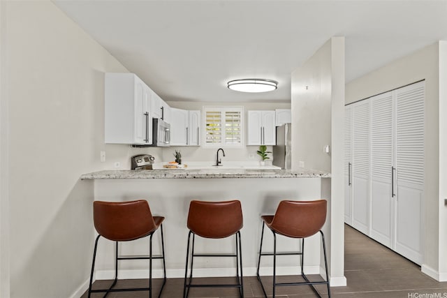 46-109 Konohiki St Unit 3922, Kaneohe, HI 96744 - kitchen with stainless steel appliances, a kitchen breakfast bar, white cabinets, a peninsula, and light stone counters