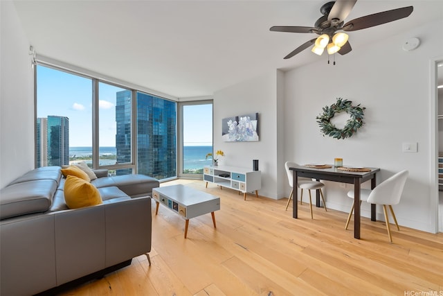 1001 Queen St Unit 2506, Honolulu, HI 96814 - living room with light wood-style flooring, a ceiling fan, a water view, and floor to ceiling windows
