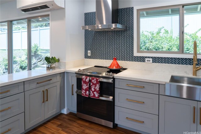 1207 Lilo Pl, Honolulu, HI 96822 - kitchen featuring double oven range, wall chimney range hood, gray cabinetry, an AC wall unit, and backsplash