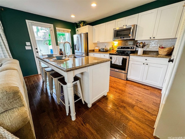 91-1356 Kaileolea Dr, Ewa Beach, HI 96706 - kitchen featuring appliances with stainless steel finishes, dark wood-style flooring, white cabinetry, tasteful backsplash, and a kitchen island with sink